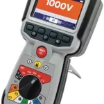 Handheld insulation tester showing 1000V on the screen, red TEST button, and a multicolored mode dial (Megger IMT100).