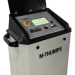 Portable industrial equipment with a hinged lid open, showing a control panel, display screen, emergency stop button, and labeled M-THUMP5 on the front.